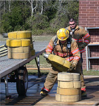 Firefighter stacking rolled hoses